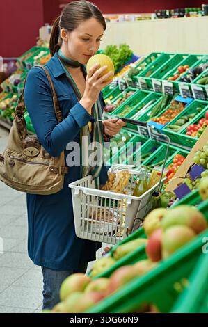 Donna che fa shopping in un negozio di alimentari, puzza di frutta con vari prodotti sullo sfondo. Germania Foto Stock