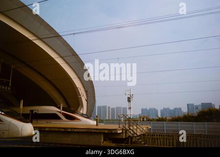 Treni ad alta velocità in una stazione moderna con skyline urbano sullo sfondo. Chengdu, Sichuan, Cina Foto Stock