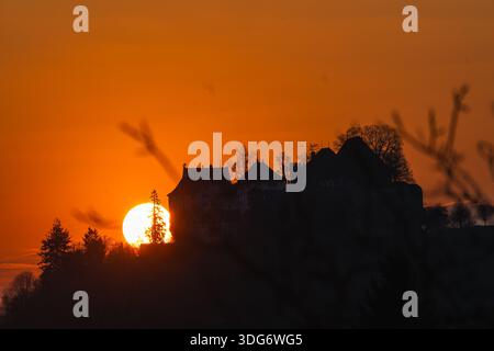 L'imponente castello di Lenzburg si erge in una sagoma forte contro un'alba ardente, affacciato sulla regione di Seetal in Svizzera. La calda luce dorata Foto Stock