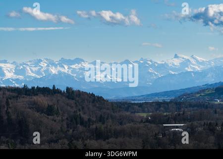 Una vista mozzafiato cattura la maestosità delle Alpi, con cime innevate che si innalzano sopra lussureggianti e verdi valli bagnate dalla luce solare di un Foto Stock