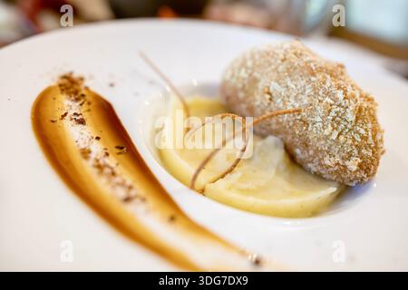 Vista dettagliata della tradizionale cotoletta di pollo di kiev impanata con purè di patate su un piatto firmato. Presentazione gastronomica professionale e foo nazionale Foto Stock