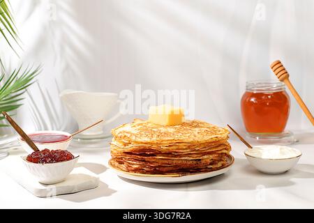 Deliziosi pancake russi con marmellata, formaggio fresco, conserve e miele su un tavolo di marmo. Colazione sana a base di ingredienti naturali, Mas Foto Stock