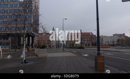 Una vista a livello della strada di una strada cittadina a Katowice, Polonia, caratterizzata da edifici a più piani con architettura storica su entrambi i lati della strada sottostante Foto Stock
