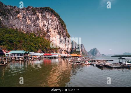 Koh Panyee. Febbraio 2025, Thailandia. Villaggio costiero di pescatori con fattorie galleggianti di pesci e case colorate sotto le torreggianti scogliere calcaree Foto Stock