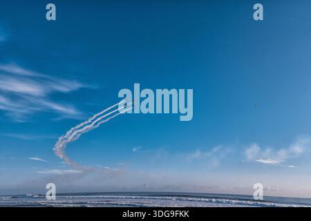 Tre aerei che volano nel cielo con piste di fumo dietro di loro. Il cielo è limpido e blu senza nuvole Foto Stock
