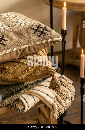 Uno scatto ravvicinato di un ambiente interno accogliente con una pila di cuscini testurizzati con ricami geometrici e nappine. Foto Stock