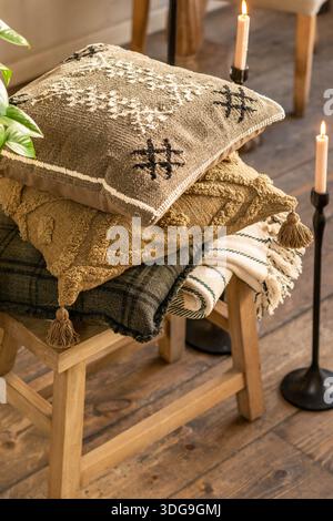 Uno scatto ravvicinato di un ambiente interno accogliente con una pila di cuscini testurizzati con ricami geometrici e nappine. Foto Stock