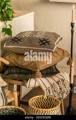 Uno scatto ravvicinato di un ambiente interno accogliente con una pila di cuscini testurizzati con ricami geometrici e nappine. Foto Stock