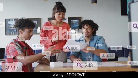 Discutere di squadra con maglione e camicie in corallo che esaminano documenti nella sala riunioni, con sovrapposizioni Foto Stock