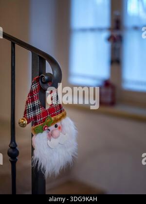 Ornamento natalizio dorabile di peluche di Babbo Natale con cappello a quadri su ringhiera in ferro battuto. Foto Stock