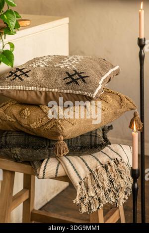 Uno scatto ravvicinato di un ambiente interno accogliente con una pila di cuscini testurizzati con ricami geometrici e nappine. Foto Stock
