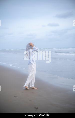 Giovane donna in piedi con calma vicino a Ocean Shore Foto Stock
