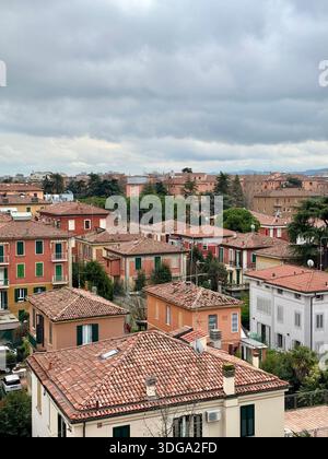 Vista su un'area residenziale in una città italiana con tetti tradizionali in terracotta e case pastello sotto un cielo nuvoloso, che mostrano la vita quotidiana urbana Foto Stock