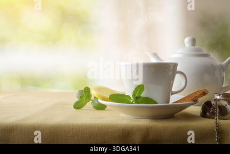 Tè verde alla menta e al limone servito al momento in bicchieri di ceramica su un tavolo con tovaglia marrone nel soggiorno. Vista frontale. Foto Stock