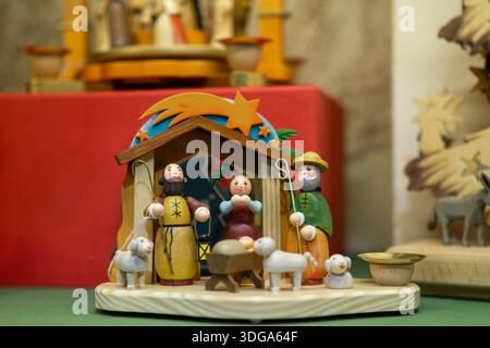 Presepe in legno artigianale che mostra la Sacra famiglia in un piccolo presepe con pastori e animali. Foto Stock