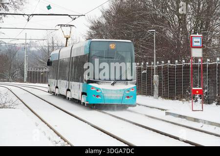 Il moderno tram elettrico si sposta lungo le rotaie in inverno. Foto Stock