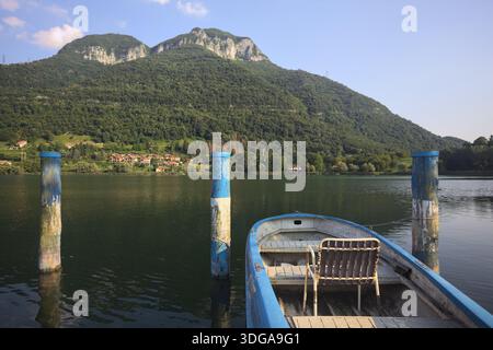 Barca ormeggiata con una sedia vuota su un lago di montagna al tramonto Foto Stock
