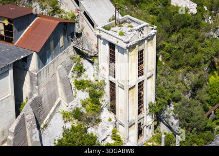Veduta aerea dell'architettura industriale abbandonata, dove strutture in cemento incontrano una vegetazione lussureggiante, una testimonianza silenziosa del passaggio del tempo, Cave del Predil, Foto Stock