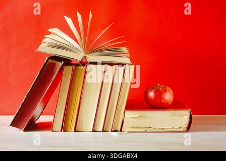 Sistemazione di libri d'epoca. Ritorno a scuola, istruzione, lettura, apprendimento, conoscenza è concetto di potere con libro aperto, una mela e spettacoli. Foto Stock