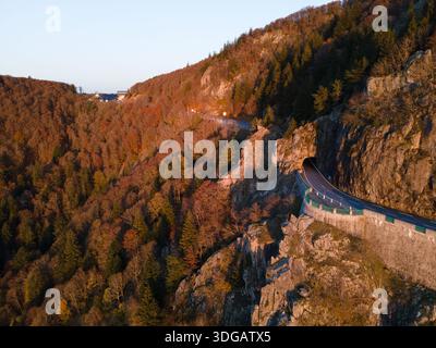 Famosa strada di montagna col de la Schlucht bagnata dalla luce dorata del mattino, circondata da fogliame autunnale, che si snoda attraverso i monti Vosgi in Francia. Foto Stock