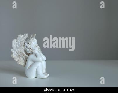 Statuetta angelica in ceramica bianca su sfondo bianco per il design. Fede, simboli e tradizioni. Foto Stock