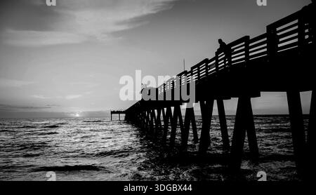 Uomo che guarda il tramonto dal molo dei pescatori di Venezia sul Golfo d'America, formalmente il Golfo del Messico al tramonto a Venice, Florida, USA Foto Stock