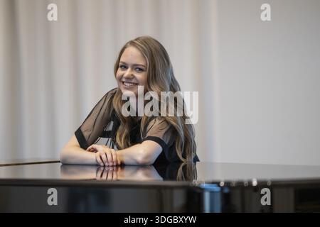 Giovane donna sorridente, pianista, in abito da sera appoggiata su un pianoforte a coda Steinway & Sons, Stoccarda, Baden-Wuerttemberg, Germania Foto Stock