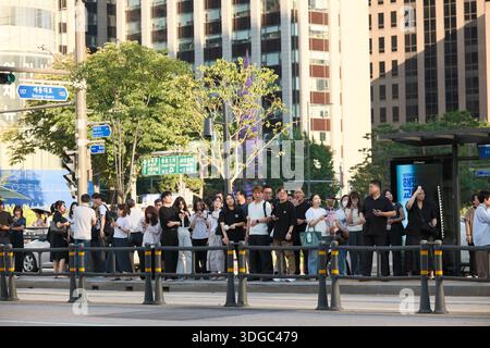 Seoul, Corea del Sud: Un grande gruppo di pedoni attende ai semafori vicino alla fermata dell'autobus e ai segnali stradali prima di attraversare un trafficato incrocio urbano Foto Stock
