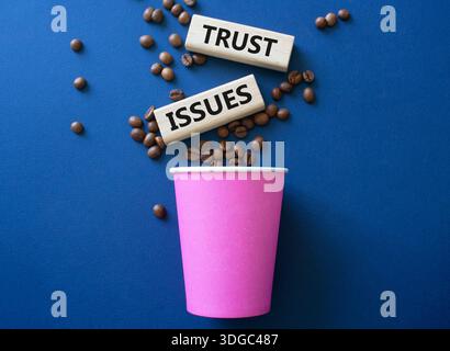 Simbolo dei problemi di fiducia. Blocchi di legno con parole problemi di fiducia. Splendido sfondo blu intenso con tazza di caffè e chicchi di caffè. Problemi aziendali e di fiducia Foto Stock