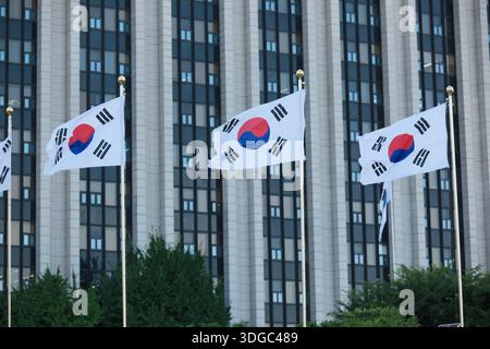 Seoul, Corea del Sud: Bandiere nazionali sudcoreane che sventolano su palchi di fronte alla facciata del moderno edificio governativo Foto Stock
