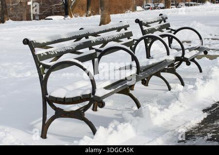 due panchine vuote coperte di neve in un parco cittadino innevato in una fredda giornata invernale Foto Stock