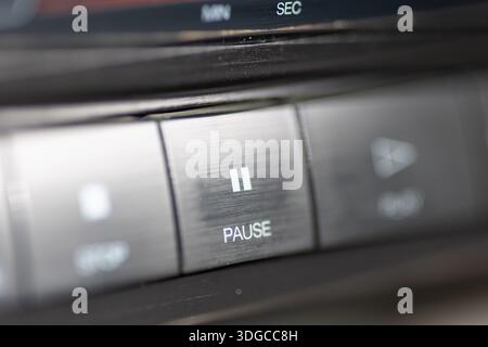 Vista ravvicinata di un'autoradio con un pulsante di pausa, eleganti comandi metallici e cruscotto sfocato. Ideale per temi di mu Foto Stock