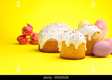 Deliziose torte di Pasqua, uova e tulipani su sfondo giallo Foto Stock