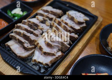 Yongin, Corea del Sud: Pancetta di maiale bollita a fette e servita su piatto caldo con contorni tradizionali coreani Foto Stock