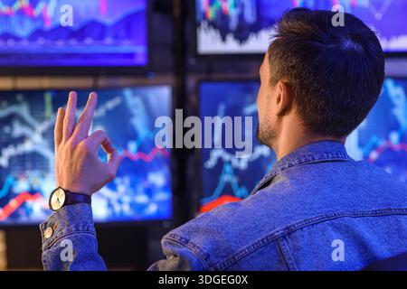 Commerciante di sesso maschile che si mostra in ufficio di notte, vista posteriore Foto Stock