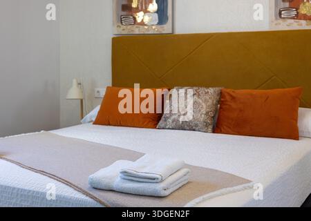 Interni caldi e moderni con illuminazione soffusa, cuscini decorativi e asciugamani piegati puliti Foto Stock