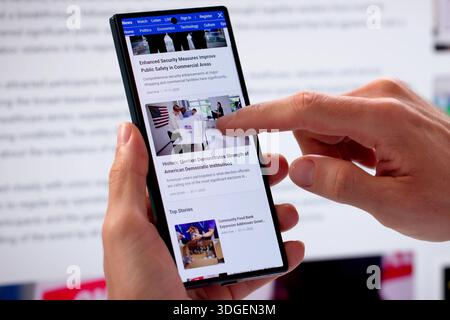 Uomo che legge articoli online sullo schermo del telefono cellulare e del notebook, Digital Marketer Foto Stock