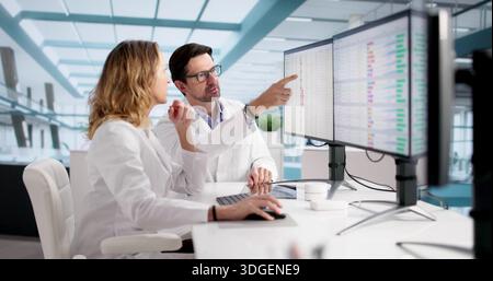 Professionisti medici che lavorano su codici di fatturazione e audit su più monitor. Foto Stock