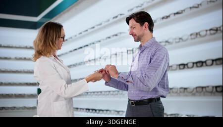 Uomo maturo alla ricerca di occhiali correttivi con Optical Professional Foto Stock