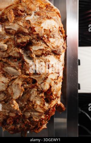 Una girarrosto verticale ruota strati di carne condita per lo shawarma. Foto Stock