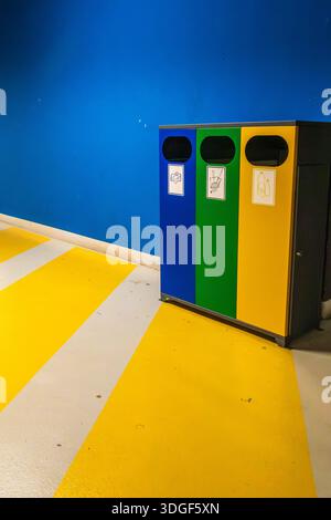 Contenitori di riciclaggio colorati per lo smistamento dei rifiuti in un garage sotterraneo, simbolo della sostenibilità e del sistema di riciclaggio urbano. Foto Stock