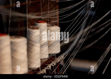 Steli in tessuto con filetto in fibra naturale allineati su un tradizionale telaio in legno, per preparare l'intricato processo di tessitura di tessuti o tessuti, rere Foto Stock