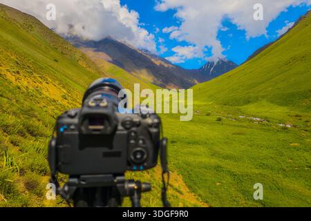 La fotocamera posizionata sul treppiede cattura paesaggi mozzafiato di montagna durante il giorno. L'atmosfera serena mostra la tranquillità e la bellezza della natura. Foto Stock