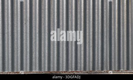 Frammento di recinzione in metallo galvanizzato con superficie ondulata in argento lucido come fondo liscio e luminoso vuoto Foto Stock