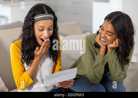 Mamma e figlia adolescente diverse leggono lettere di white paper che coprono la bocca Foto Stock