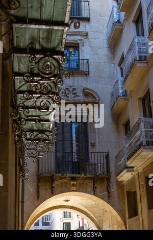 Vista attraverso uno storico arco in pietra presso l'Ayuntamiento de Alicante, il municipio di Alicante, Spagna. L'architettura barocca presenta ferro ornato Foto Stock