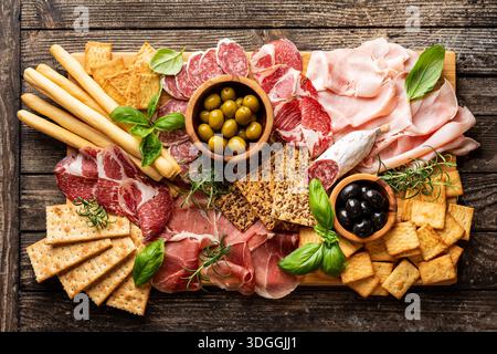 Antipasti con diversi antipasti, salumi, spuntini e vino rosso. Salsiccia, prosciutto, tapas, olive e cracker per un buffet party. Vista dall'alto, disposizione piatta Foto Stock