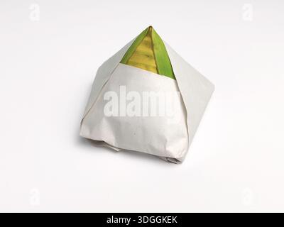 Primo piano dell'autentico bungkus nasi lemak avvolto in carta e foglia verde di banana isolata sul bianco Foto Stock