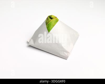 Primo piano dell'autentico bungkus nasi lemak avvolto in carta e foglia verde di banana isolata sul bianco Foto Stock