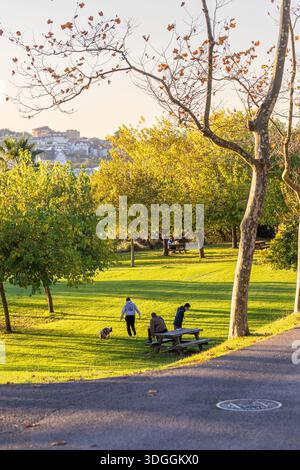 Santander, Spagna – 19 novembre 2021: Le persone e i loro animali si godono la luce dell'ora d'oro in un pomeriggio d'autunno soleggiato nel parco pubblico sulla Magdalena Pen Foto Stock